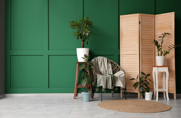 Stylish interior of living room with armchair, houseplants and folding screen