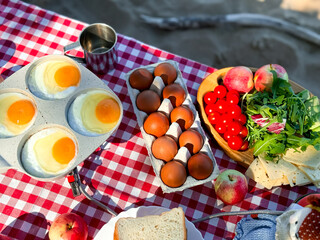 Sunny breakfast spread with eggs and fresh produce on checkered tablecloth