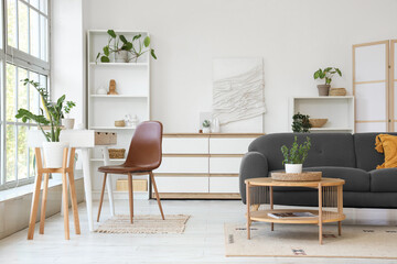Interior of light living room with programmer's workplace, sofa and shelf units