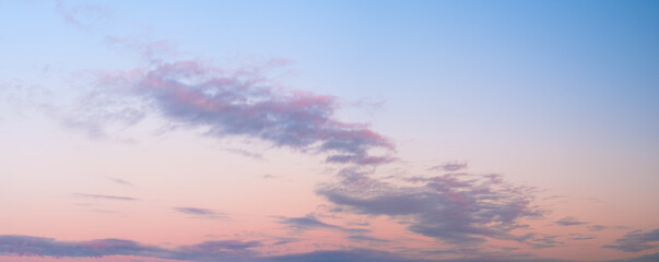 A beautiful blue sky with a few clouds and a pinkish hue. sky is calm and peaceful, and the clouds...