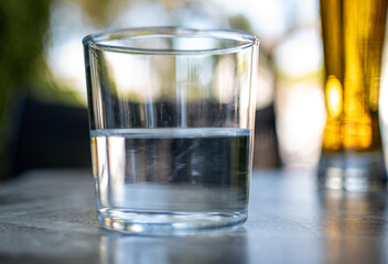  A half empty or a half full glass of water on a table with nice blurry background.