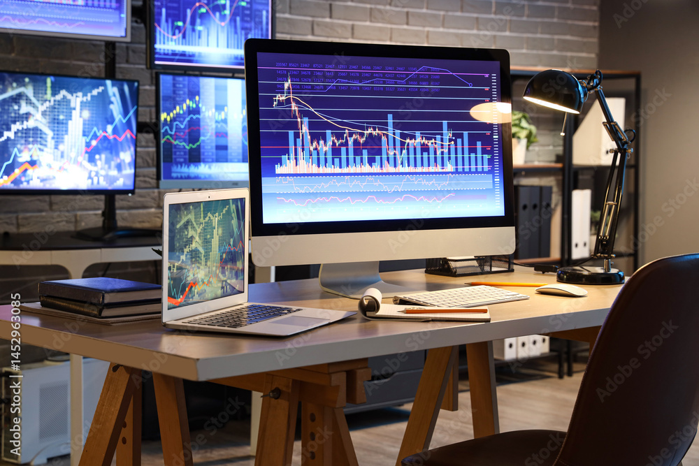 Aufkleber computer and laptop with stock data on trader's desk in dark office