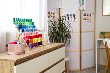 Organizer with thread spools and sewing supplies on commode in atelier