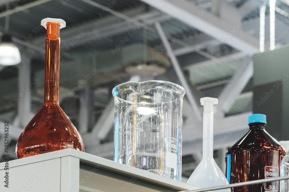 Poster On the shelf there are several glass flasks and microspheres of different sizes and colors, the large flask is brown. The scene creates an atmosphere of science or a laboratory.