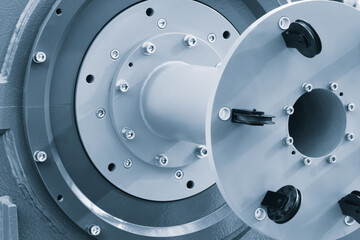 A metal part is a shaft with a hole in the middle. The hole is surrounded by many screws. The...