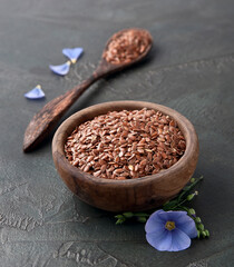 Flax seed in wooden plate and flax flower