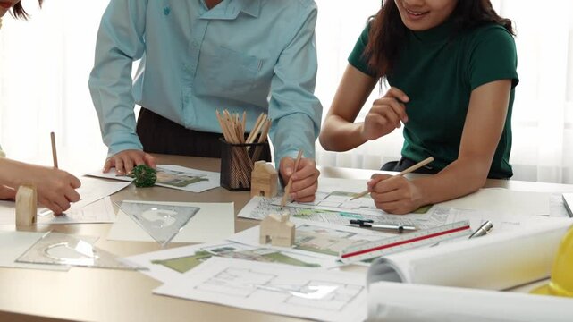 A video of architect use measurement tools and pencil to measure blueprint. Architect design house construction on a table at studio, with architectural plan scattered around. Focus hand. Delineation.