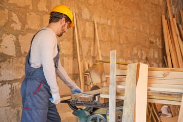 Male carpenter sawing wooden plank at sawmill
