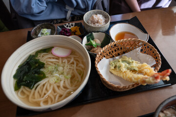 Japanese udon set with tempura shrimp and vegetables being served on a tray