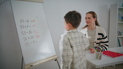 Diligent pupil writing whiteboard at school closeup. Child boy solving equations