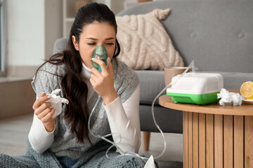 Ill young woman using nebulizer at home