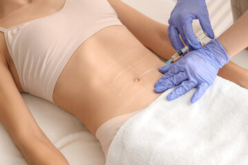 Young woman receiving injection in her belly at cosmetologist's office, closeup