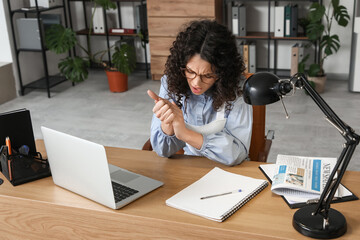Young businesswoman suffering from pain in her hand at office