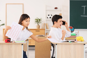 Teenage girl peeping at her classmate's results of school test in classroom