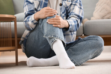Young woman in stylish white socks sitting on floor at home