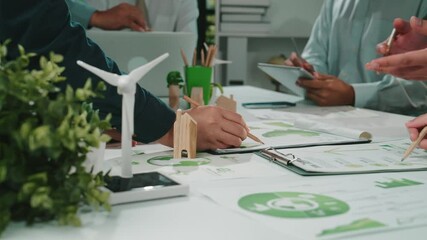 A diverse business team engages in a collaborative workshop, focusing on sustainability and eco-friendly initiatives, while analyzing graphs and developing strategies. SACTR