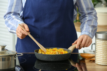 Woman frying pilaf on stove in kitchen, closeup