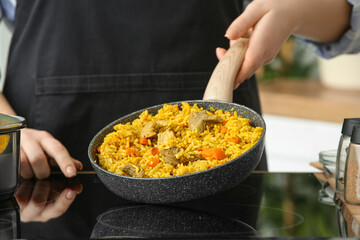 Woman frying pilaf on stove in kitchen, closeup