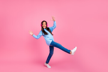 Joyful preteen girl with headphones showing playful gestures on pink background, expressing fun and...