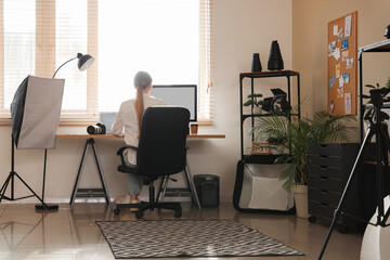 Female photographer working with computer at table in office, back view