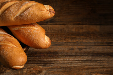 Wicker bowl with fresh baguettes on wooden background