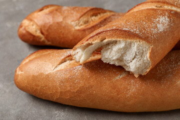 Fresh baguettes on grey background, closeup