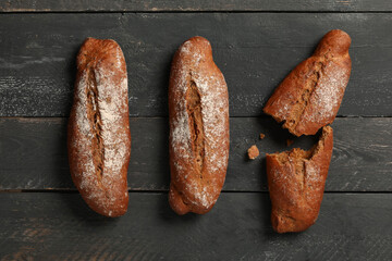 Fresh rye baguettes on black wooden background