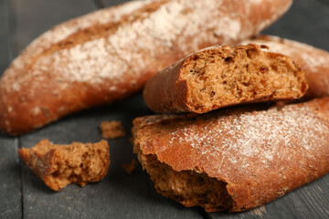 Fresh rye baguettes on black wooden background, closeup