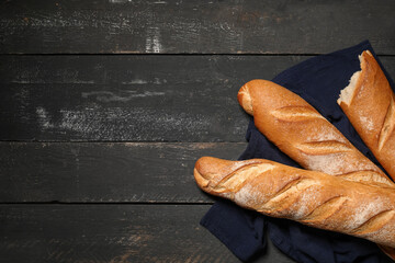 Fresh baguettes on black wooden background