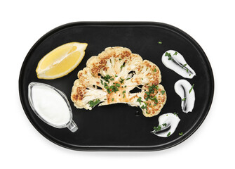 Plate of grilled cauliflower steak with lemon and sauce on white background