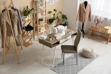 Interior of atelier with tailor's workplace, clothes rack and mannequin