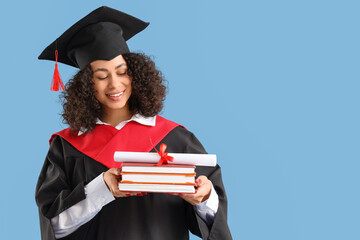 Pretty African-American female graduate with diploma and books on blue background