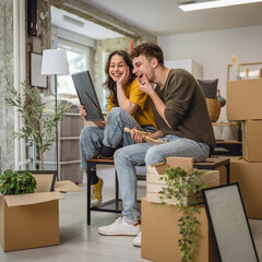 Fototapeta premium Happy adult couple having fun while unpacking boxes together