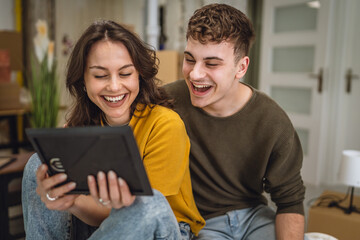 Delight happy couple look at picture in photo frame around boxes