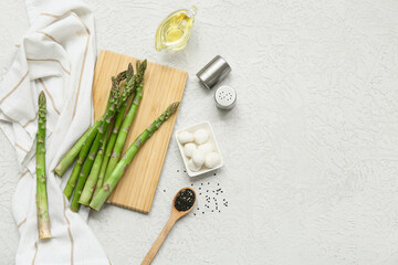 Wooden board with fresh green asparagus and mozzarella cheese on white background