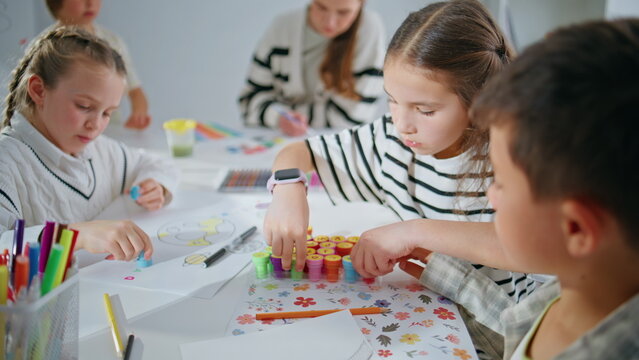 Focused kids playing stamps in school classroom closeup. Small pupils creating