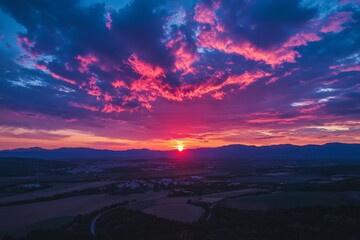 Vibrant pink and purple sky with clouds at sunset, silhouetted against mountain horizon.