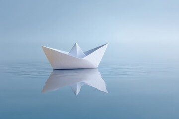 Obraz premium Paper boat floats on calm blue water reflecting serenity.
