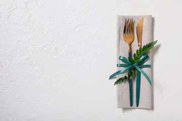 Stylish golden cutlery with fresh leaf on white background