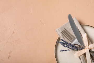 Beautiful table setting with silver cutlery and lavender flowers on beige background