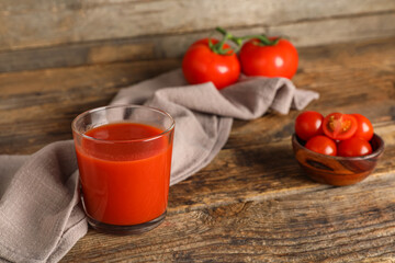 Glass of fresh tomato juice and vegetables on wooden background