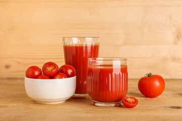 Glasses of fresh tomato juice and vegetables on wooden background