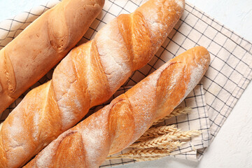 Fresh baguettes and wheat on light blue background, closeup