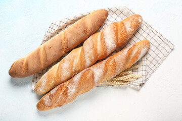 Fresh baguettes and wheat on light blue background