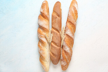 Fresh baguettes and wheat on light blue background