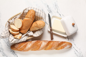 Basket with fresh baguettes and butter on white background