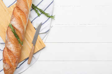 Wooden board with fresh baguette and rosemary on white wooden background