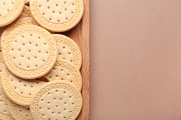 Wooden board with sweet cookies on brown background