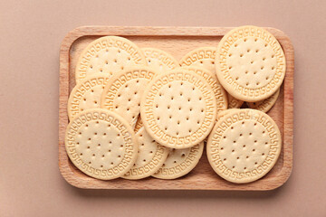 Wooden board with sweet cookies on brown background