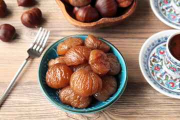 Traditional Turkish Candied Chestnuts designed in blue ceramic on wooden surface with coffee	